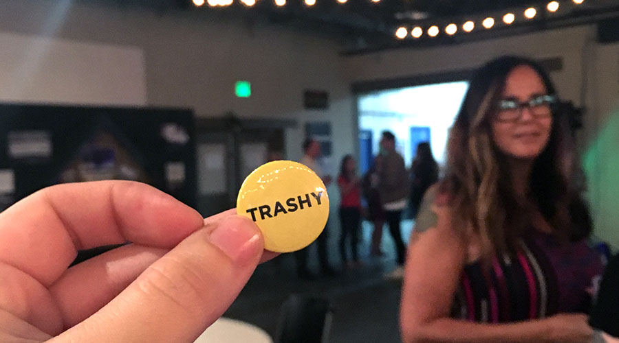 close up of a hand holding a yellow pin that says trashy at the AAF Trashy Awards