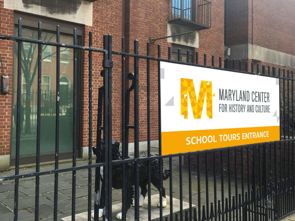 An MCHC sign on a metal fence.
