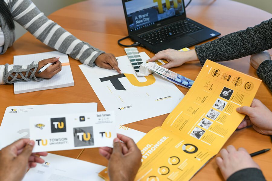 A marketing team weighing color options when selecting final colors for the TU logo.