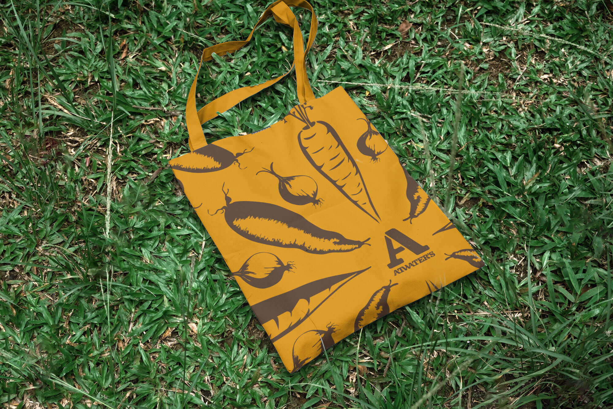 Tote bag with vegetable print and Atwater’s branding laying on grass