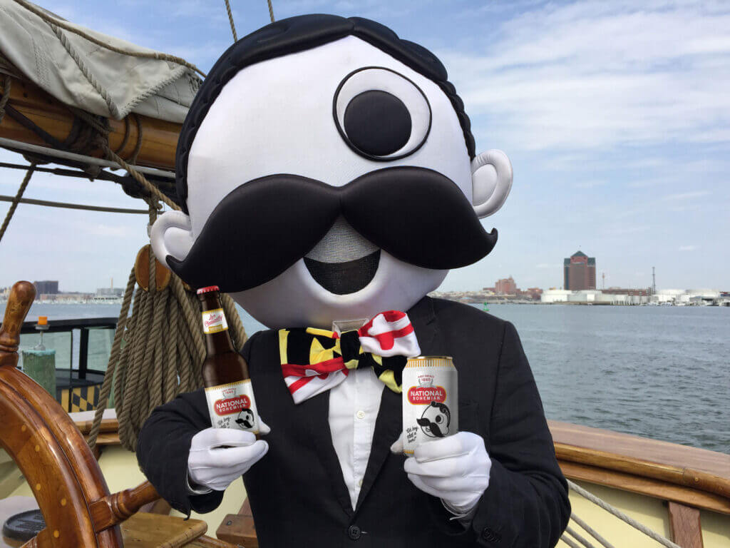 The National Bohemian mascot poses with a bottle and can of beer in a boat on Baltimore’s waterfront.
