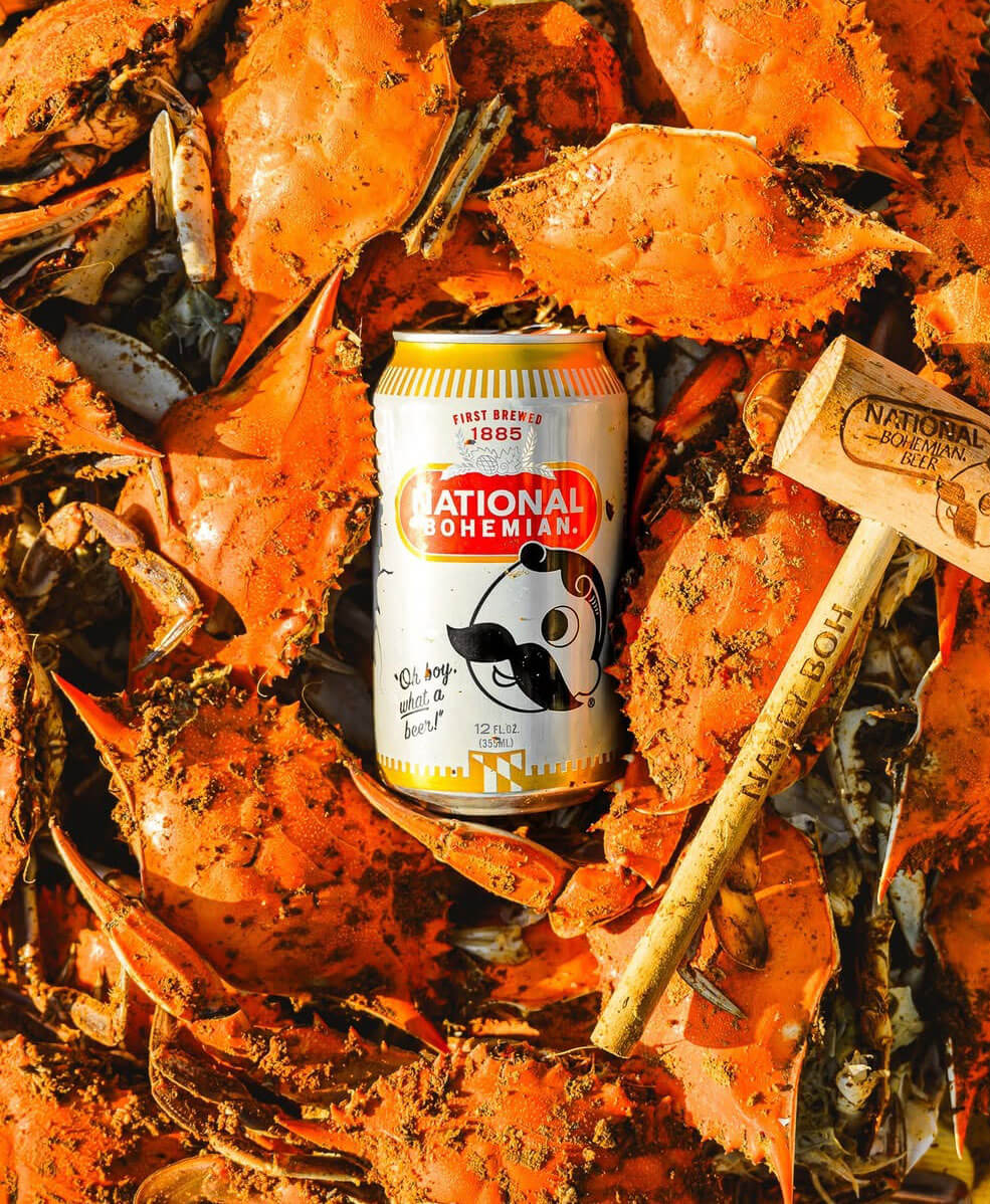 A can of National Bohemian beer among a pile of cooked crabs.