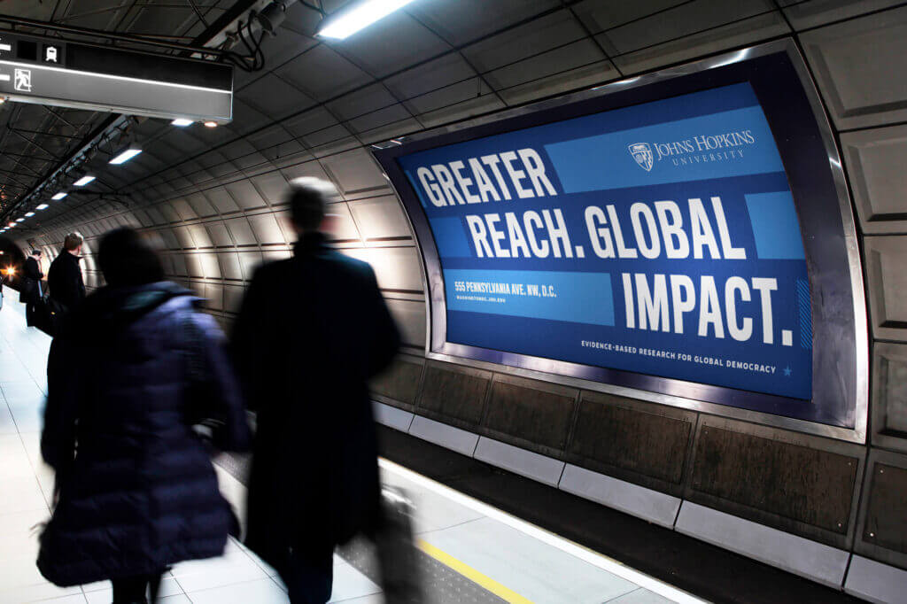 A mocked-up advertisement on the walls of a metro station reading “Greater Reach. Global Impact.”
