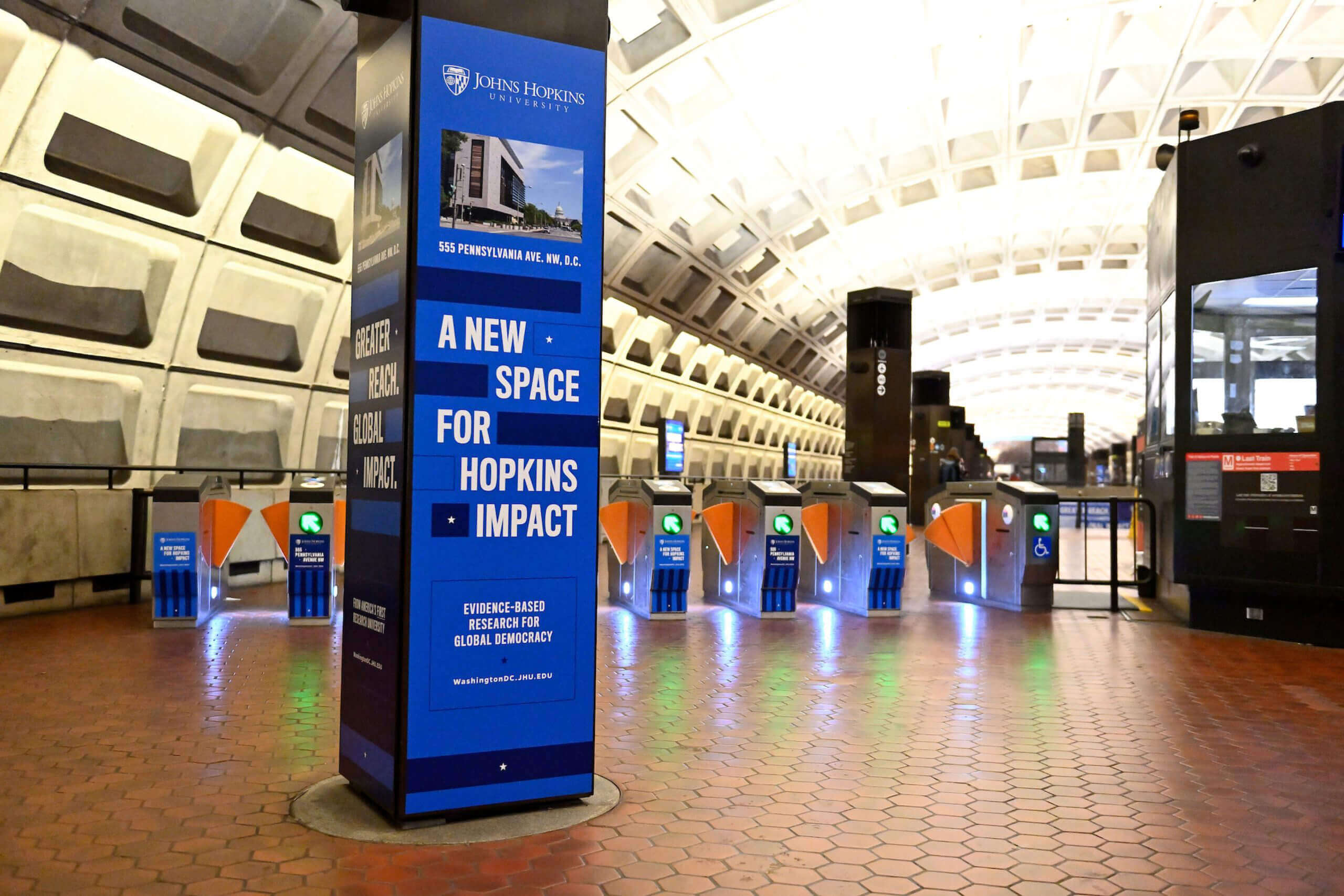 An advertisement on a column in a D.C. Metro station featuring a key campaign message, “A New Space for Hopkins Impact.”