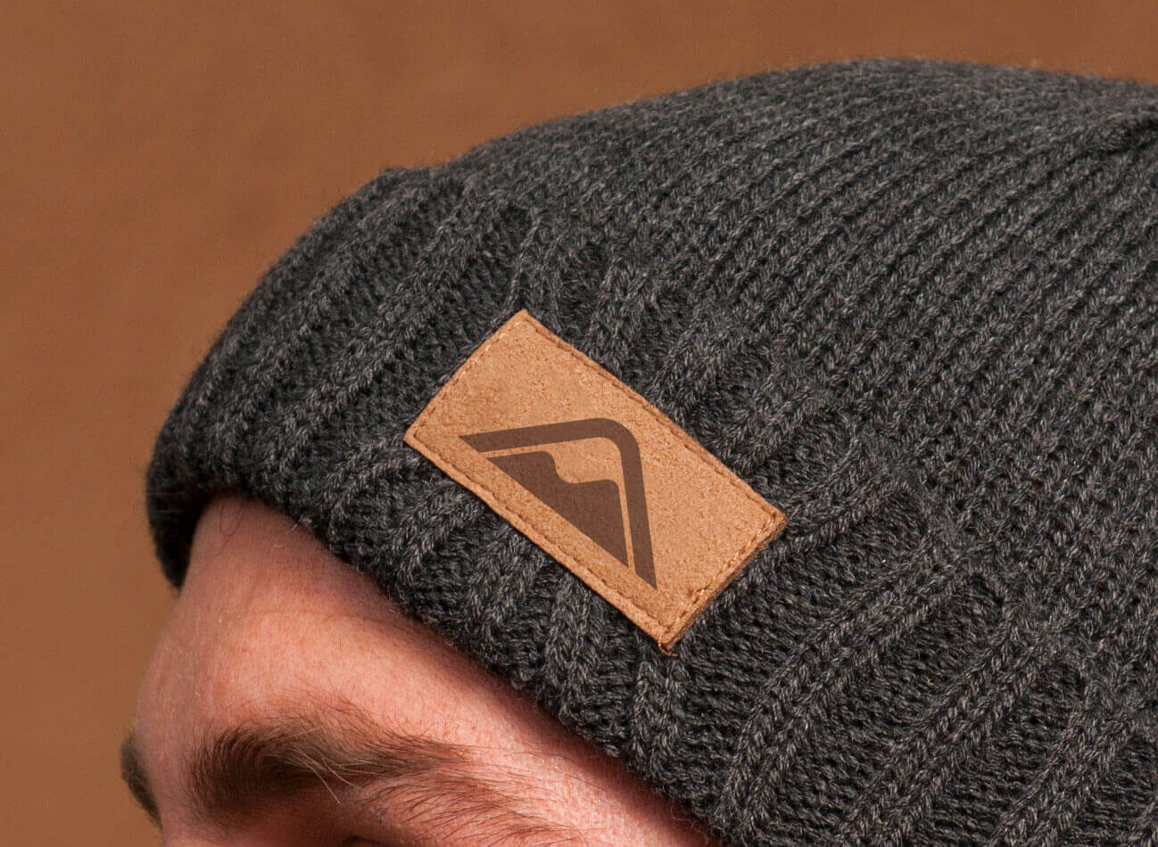 Detail shot of a man wearing a branded beanie.