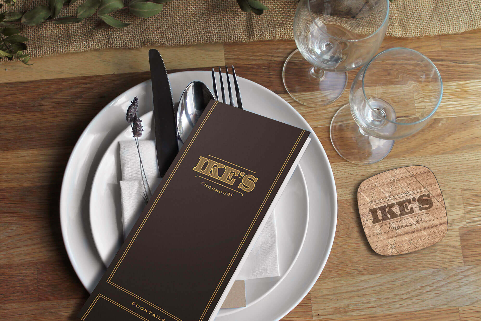 Ike’s Chophouse menu on top of plate and utensils with two glasses and a coaster at right.