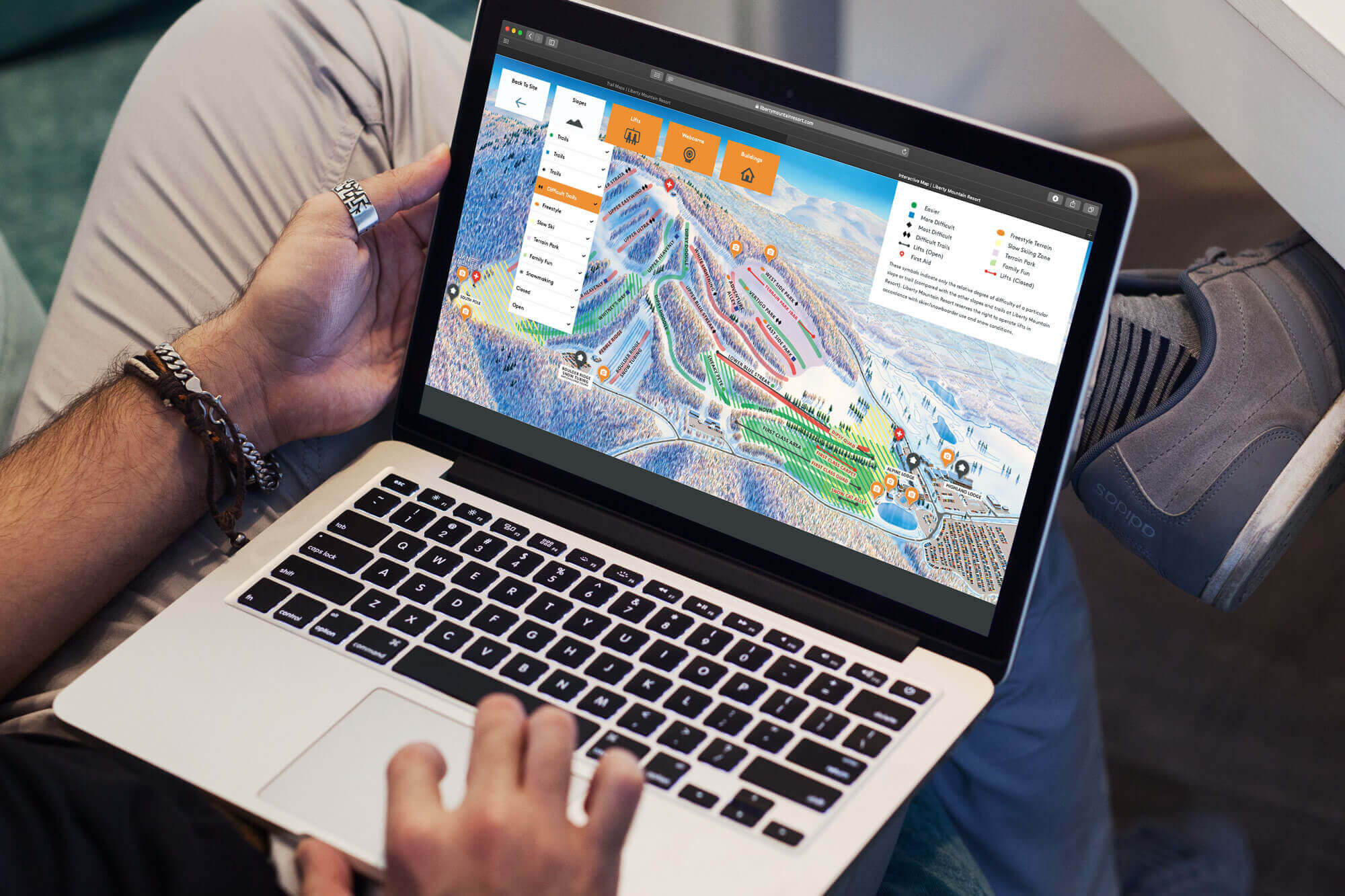 Man holding laptop open to ski map.
