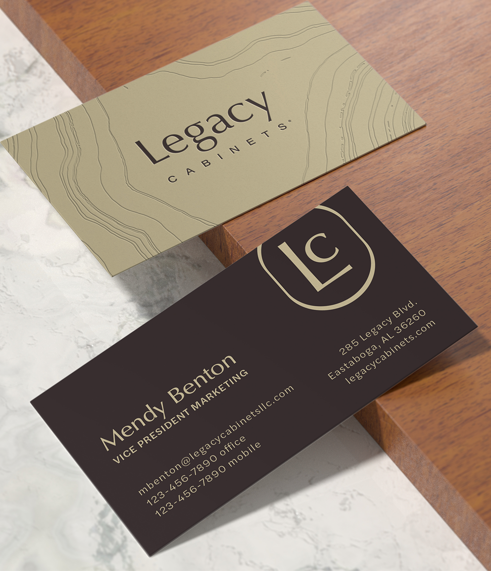 Legacy Cabinets business cards displayed on wood and stone surfaces, featuring the LC monogram, topographic line pattern, and contact details in an elegant neutral and dark color palette.
